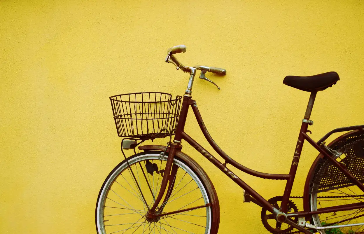 Brown bicycle in front of a yellow wall